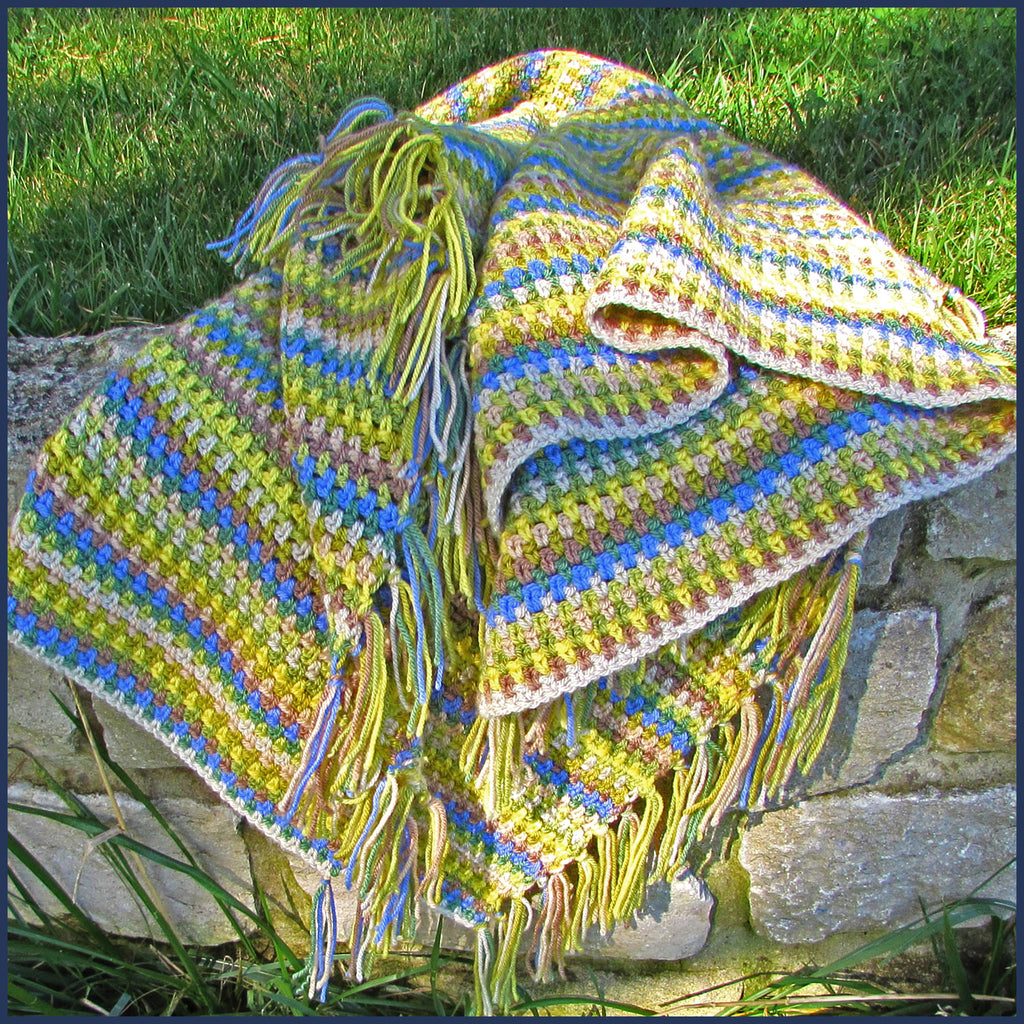 stripey crochet blanket on a garden wall