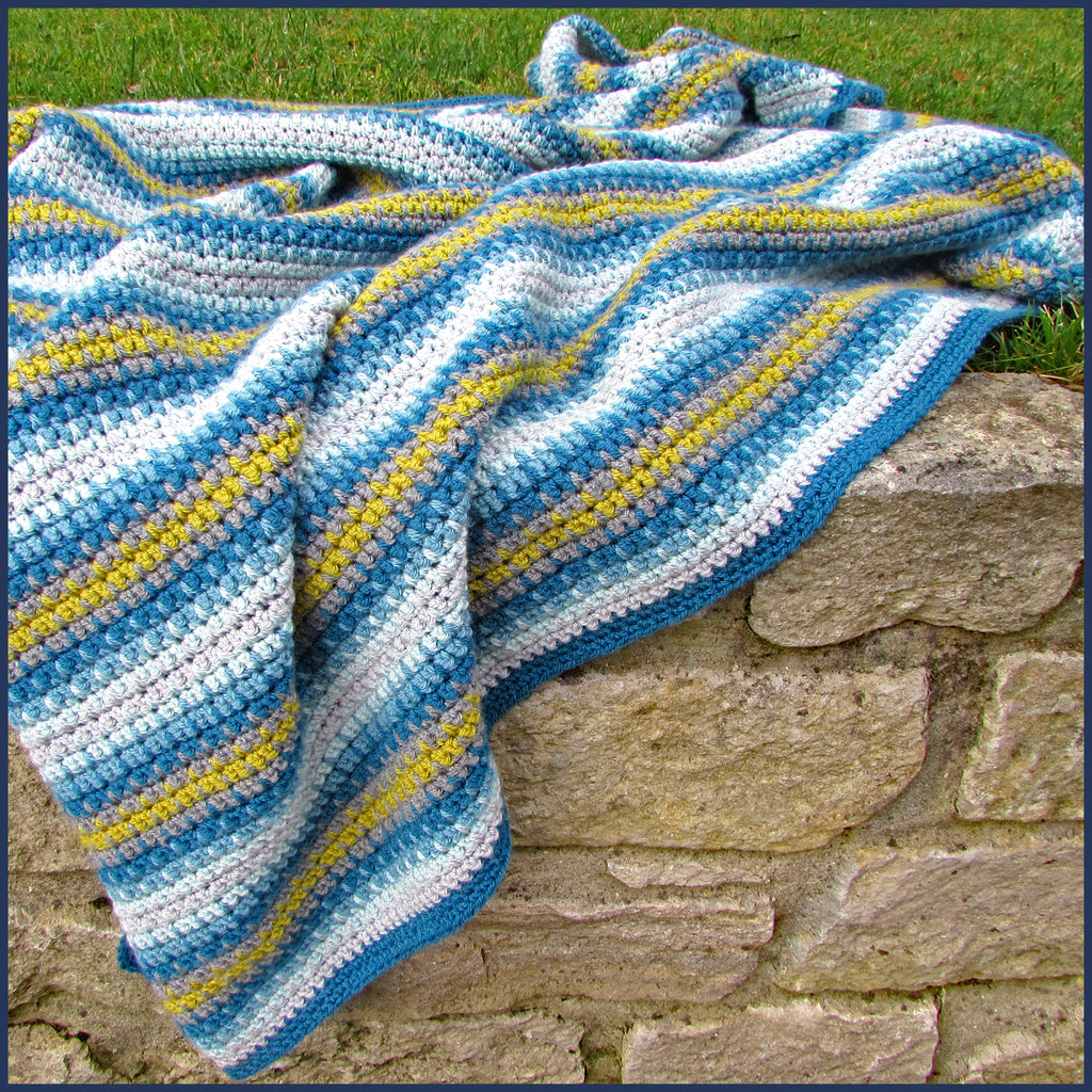 stripey crochet blanket on a garden wall