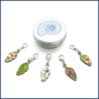 five colourful enamel leaf stitch markers with ammonite tin