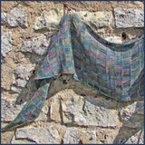 green/rainbow crochet shawl against a stone wall