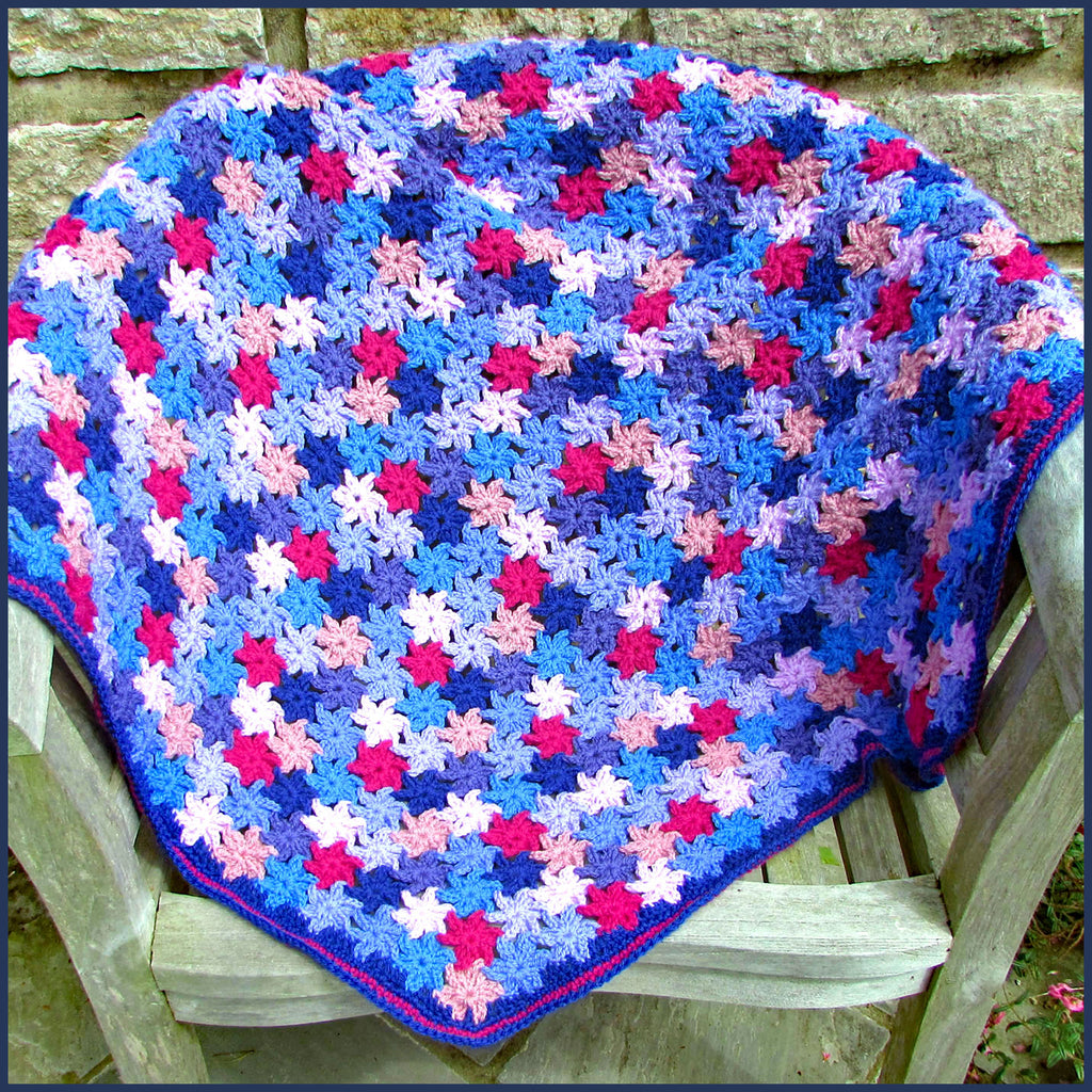 crochet flower blanket on a wooden bench