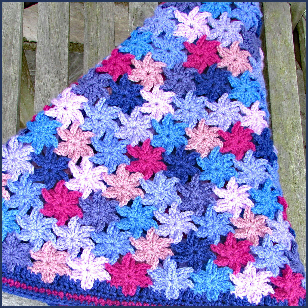 crochet flower blanket folded on a wooden bench