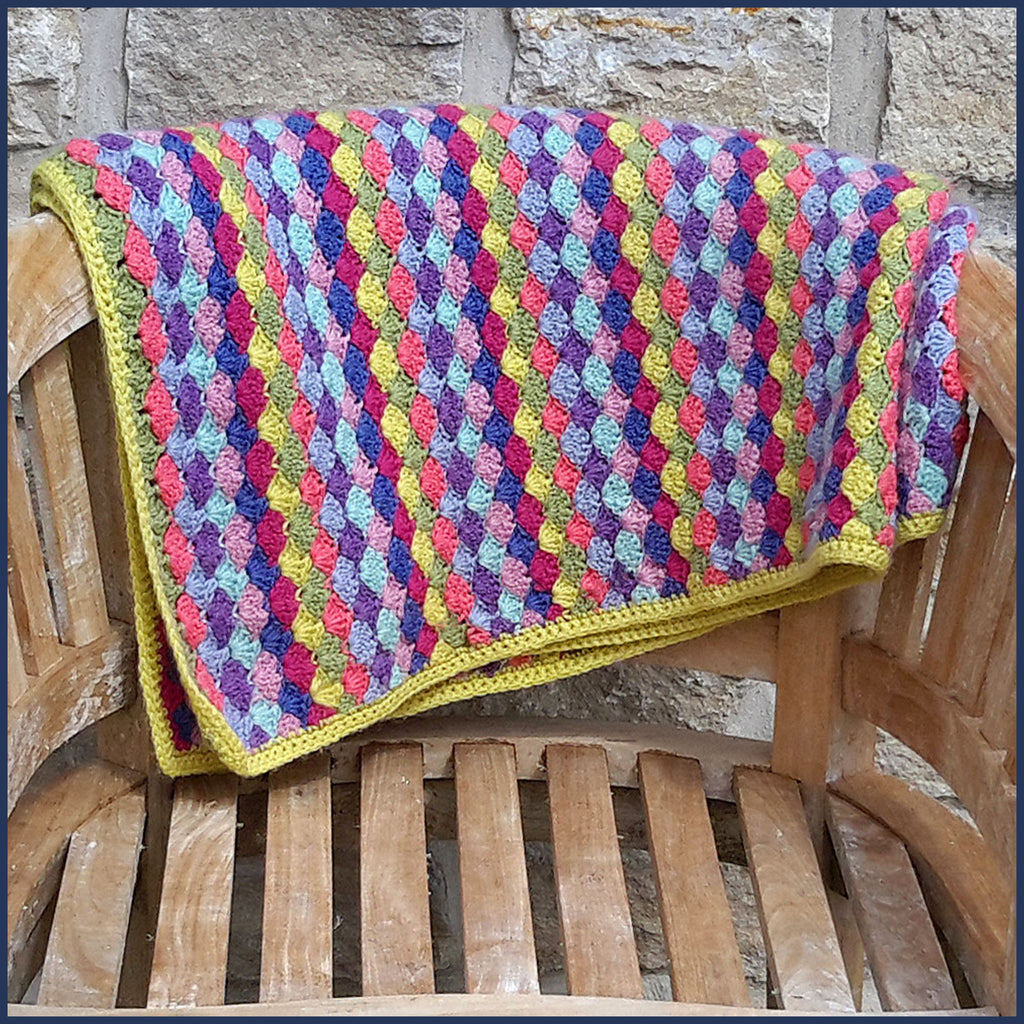 shell stitch crochet blanket folded on a garden chair