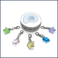 five glass star stitch markers with an ammonite tin