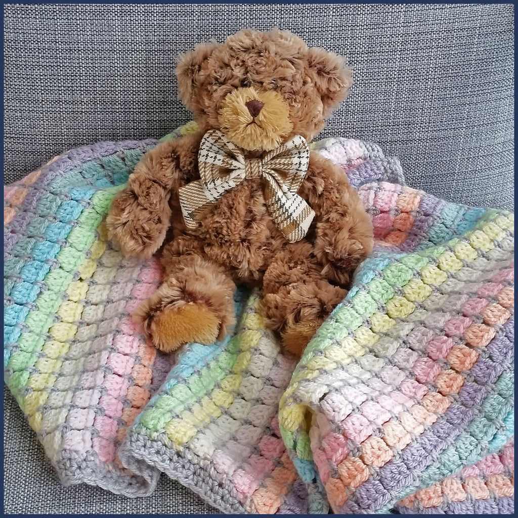 rainbow crochet baby blanket close up with teddy