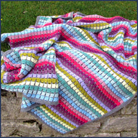 rainbow crochet blanket on a garden wall