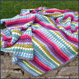 rainbow crochet blanket on a garden wall